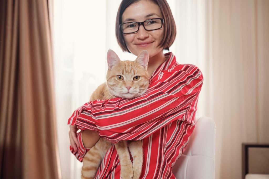 business woman in a red shirt with a ginger cat at home